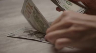 Masadaki 100 dolarlık banknotları sayarken yakın plan çekimler.