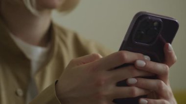 Mor çantalı akıllı telefon kullanan, mesaj atan ya da yazan bir kadının elleri.