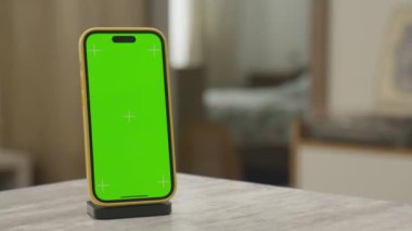 Masaya yeşil bir ekran yerleştirilmiş akıllı telefonun yörüngesinde, krom anahtar düzenleme için hazır.