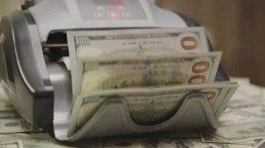 Para sayma makinesinin yakın plan çekimleri, yığınla banknot işliyor.