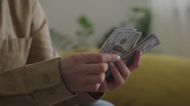 Bulanık bir geçmişi olan yüz dolarlık banknotları sayan birinin yakın plan fotoğrafı.