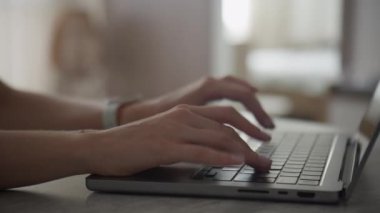 Ev ofis ortamında dizüstü bilgisayarda klavyeye yazı yazan ellerin yakın çekimi
