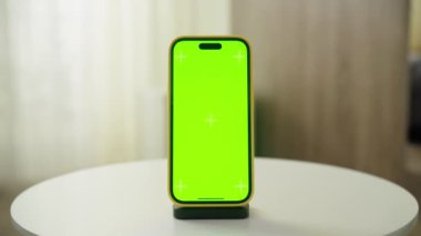Beyaz masadaki yeşil ekranlı akıllı telefon, özel içerik eklemek için ideal