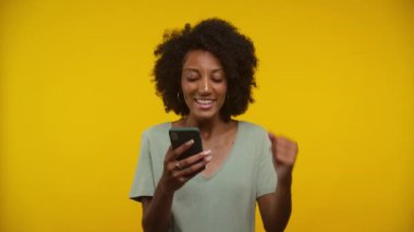 Akıllı telefondan olumlu mesaj okuyan kadın sarı arkaplanda izole edildi