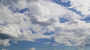 Açık mavi gökyüzü güneşli bir günde büyük, tüylü beyaz bulutlarla dolu.