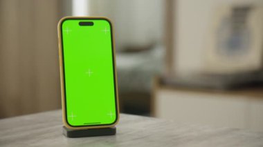 Masanın üzerine yeşil bir ekran yerleştirilmiş akıllı telefonun yörüngesinde, modern bir kapalı alan ortamında krom anahtar uygulamaları için hazır.