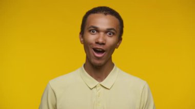 Sarı polo tişört giyen, şaşırmış bir genç adamın yakın plan portresi.