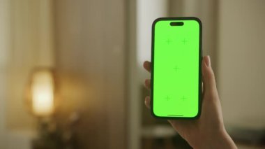 Kapalı bir ortamda yeşil ekranlı akıllı bir telefonu tutmak, kişiselleştirmeye ya da içeriği değiştirmeye hazır