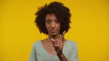 Kıvırcık saçlı genç bir kadının portresi. Parmağıyla hiçbir hareket yapmıyor. Açık yeşil bir bluz giyiyor.