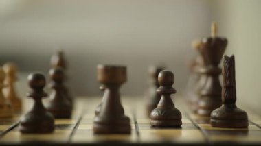 Satranç tahtasındaki ahşap satranç taşlarına yakından bakmak, piyonlara ve diğer taşlara odaklanmak, dramatik, odak dışı bir arka plan etkisi yaratır.