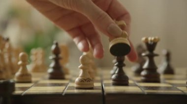 Satranç tahtasındaki satranç taşını hareket ettiren bir elin yakın çekimi stratejik oyunu gösteriyor.