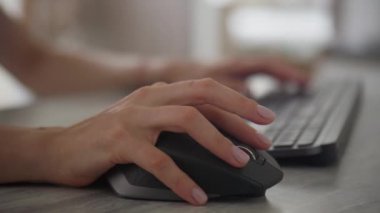 Bir eli bilgisayar faresi kullanarak ve yumuşak odaklı, minimalist çalışma alanında klavyeye yazarak kapat