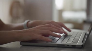 Yumuşak odaklı arka planı olan bir dizüstü bilgisayarda yazı yazan ellerin yakın çekimi, minimalist ve modern çalışma alanını yakalıyor