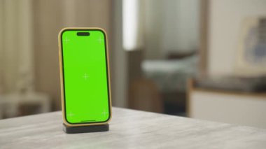 Yeşil ekranlı akıllı telefon, bir masanın üzerinde dikey duruyor, krom anahtarlama veya modelleme kullanımına hazır