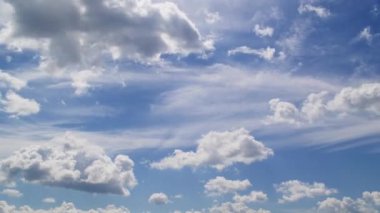 Geniş mavi gökyüzü beyaz kabarık bulutlarla dolu, barışçıl ve huzurlu bir atmosfer yaratıyor.