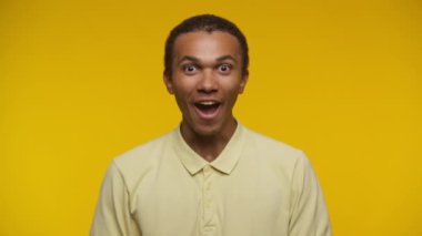 Kollarını kaldırmış neşeli bir gencin portresi, canlı sarı bir arka plana gülümsüyor ve kutluyor.