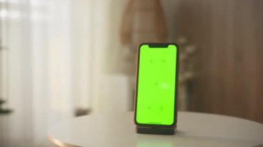 Parlak, yumuşak ışıklı bir odada yeşil ekranlı akıllı telefon, modeller için ideal.