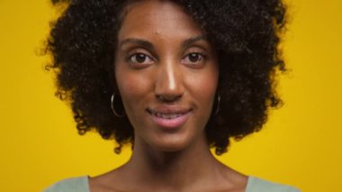 Kıvırcık saçlı gülümseyen bir kadının yakın plan portresi.