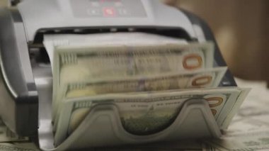 Hareket halindeki bir para sayma makinesinin yakın plan çekimi, Amerikan dolarlarını saymak, finans ve bankacılık faaliyetlerini sembolize etmek
