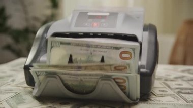 Bir para sayma makinesinin faaliyet halindeki yakın plan çekimi, bir yığın Amerikan doları banknotunu işlemek, finans ve bankacılığı vurgulamak