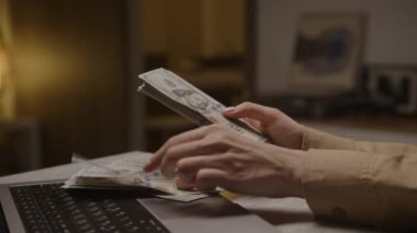 Bilgisayardan Amerikan dolarlarını sayan eller, çevrimiçi iş, finans ve mali işlemleri sembolize ediyor