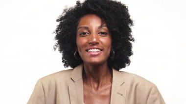 Bej ceketli neşeli bir kadın. Parlak bir şekilde gülümsüyor. Elleri havada, kıvırcık saçlı, beyaz bir geçmişi var.