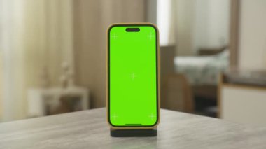 Yeşil ekran krom anahtarı olan bir akıllı telefon. Dolly zoom 'da sergileniyor. Yumuşak ışıklandırılmış kapalı bir ortamda bir masanın üzerine yerleştiriliyor.