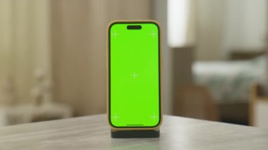 Video düzenleme ya da bileşik doli yakınlaştırma için bir masaya yerleştirilmiş krom anahtar işaretli yeşil bir ekran gösteren akıllı telefon