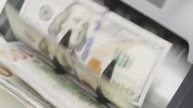 100 dolarlık banknotları işleyen para sayma makinesinin yakın plan çekimi.