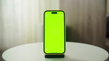 Masada dikey olarak gösterilen yeşil ekran maketli bir akıllı telefon, özelleştirmeye hazır.