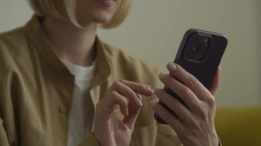 Karanlık kaplamalı akıllı telefon tutan bir kadının elleri yakın görüntüde, etkileşime odaklanıyor..