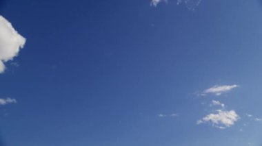 Parlak mavi bir gökyüzü, dağınık bulutlu, tüylü beyaz bulutlar huzur içinde yüzüyor.