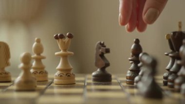 Yoğun bir oyun sırasında tahta bir satranç tahtasının üzerinde satranç taşlarını hareket ettiren bir elin yakın çekimi.