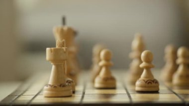 Ahşap satranç piyonları ve satranç tahtasındaki bir kale, oyunda stratejik bir oyunu temsil ediyor..