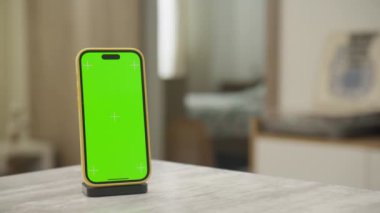 Masada yeşil renkli anahtar ekranlı akıllı telefon, ekran değişimi için ideal, modern, minimalist bir odada..
