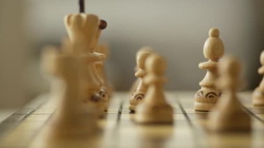 Oyunun ortasında tahta bir tahtada satranç taşlarının yakın plan görüntüsü, strateji ve alan derinliğine odaklanıyor.