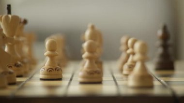 Oyuna ve karar verme mekanizmasına odaklanmış, tahta tahtada satranç taşını stratejik olarak hareket ettiren bir elin yakın çekimi.