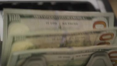 100 dolarlık banknotların yakın plan çekimi para sayma makinesinde hızla işleniyor.