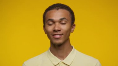 Sarı gömlekli gülümseyen genç bir adamın portresi, parlak sarı bir arka planda izole edilmiş..