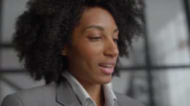 Modern bir ofis ortamında sanal bir görüntüde konuşan profesyonel bir iş kadınının yakın plan çekimi.