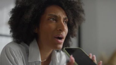 Modern ofis ortamında akıllı telefonuyla konuşan profesyonel bir kadının yakın çekimi..