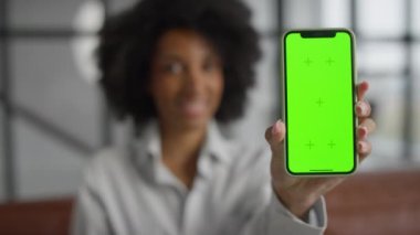 Arka planda gülümseyen biri tarafından tutulan yeşil ekranlı akıllı telefonun yakın çekimi, maketler için mükemmel..