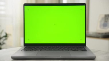 Çağdaş bir odada krom anahtar düzenleme için uygun, boş yeşil ekranlı bir dizüstü bilgisayar.