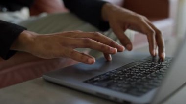Bir insanın ellerinin dizüstü bilgisayarda gezerken, şık ve çağdaş bir ofis ortamında çalışırken yakın plan görüntüsü.