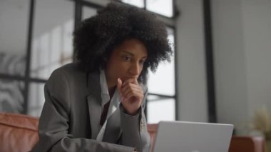 Takım elbiseli, işine dalmış, şık ve çağdaş bir ofiste oturan, işine odaklanmış genç profesyonel bir kadın..