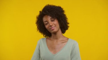 Gülümseyen bir kadın. Gözleri kapalı. Parlak sarı bir zemin üzerinde nazikçe dans ediyor..