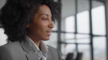 Gri takım elbiseli profesyonel bir kadının modern ofis geçmişine sahip bir video konuşması sırasında yakın plan fotoğrafı..