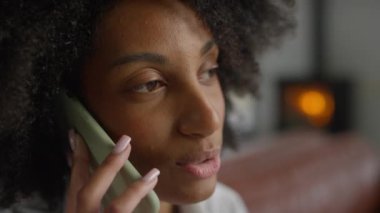 Bir kadının sıcak ve odaklanmış bir ifadeyle telefon konuşması yaparken yakın plan çekimleri..