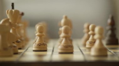 Bir eli, stratejik olarak, tahta bir satranç tahtasına siyah bir piyon yerleştirip, oyun oynamaya odaklı bir şekilde yaklaş..