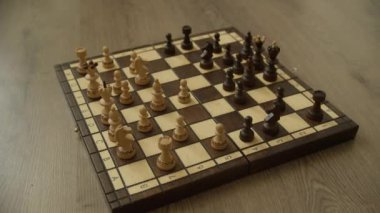 Karmaşık bir şekilde oyulmuş aydınlık ve karanlık parçalarla stratejik bir oyuna hazır ahşap bir satranç tahtası..